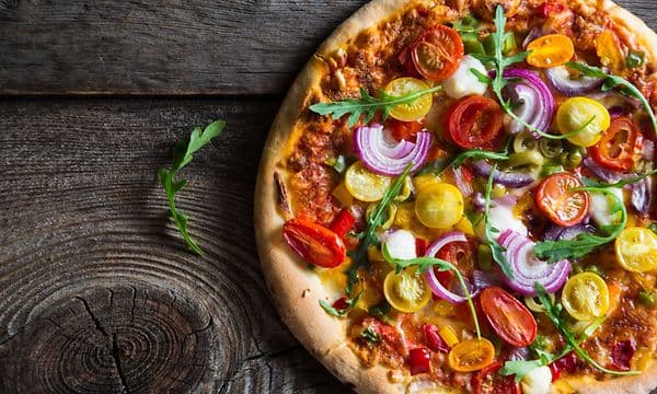 Pizza med grønnsaker på et trebord