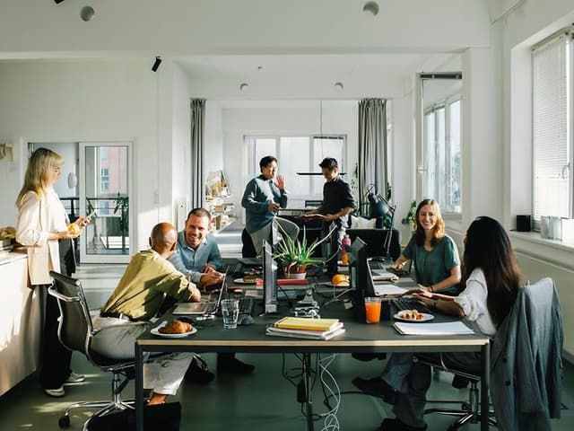 A group of employees in open office landscape, having discussions in smaller group