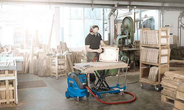 Man using professional Nilfisk vacuum in his woodshop