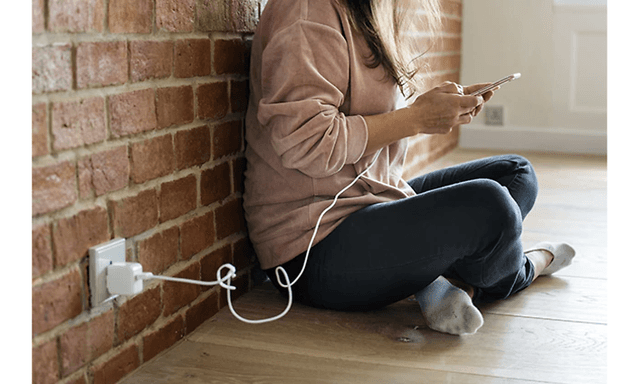 photo of a woman sitting on the floor while charging her smartphone