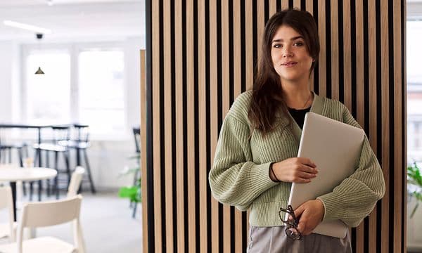 Woman standing in office holding her laptop