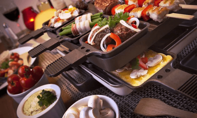 Nærbillede af en firkantet raclette fuld af mad, der tilberedes