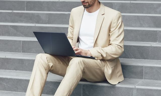 ASUS Zenbook 14 OLED i fanget på en mann som sitter i en trapp