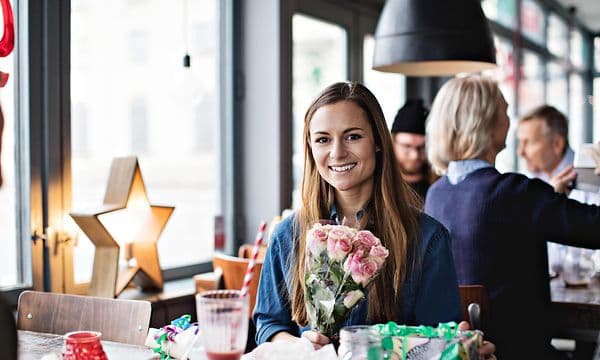 Woman in cafe with flowers and gifts around her