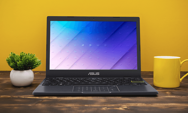 Pöydällä oleva ASUS E410KA kannettava tietokone sekä keltainen taustaväritys