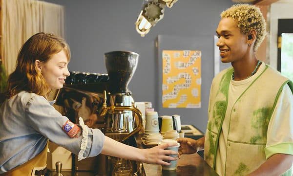 Mand bestiller kaffe på café med Sony WF-C510 in-ear høretelefoner i ørerne