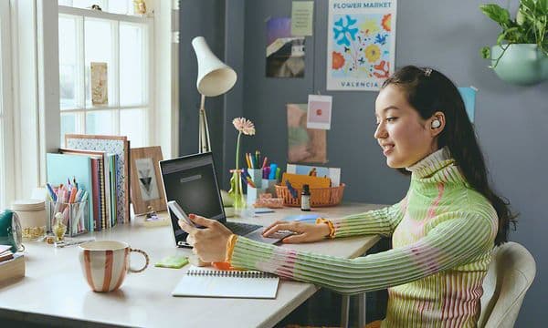Pige ved et skrivebord med Sony WF-C510 in-ear høretelefoner i ørerne