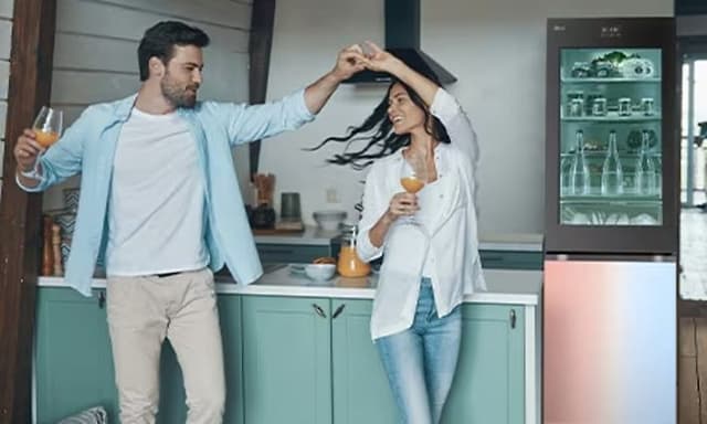 LG køle-/fryseskab og et par der danser med en drink i hånden i et køkken