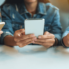 tre ungdommer bruker smarttelefon ved et bord