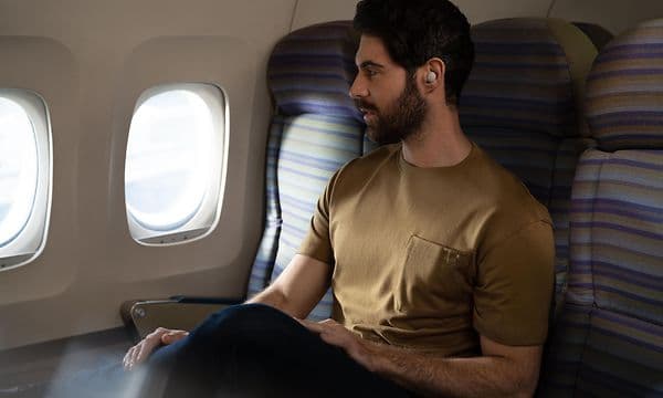 Mand med Sony in-ear høretelefoner på et fly