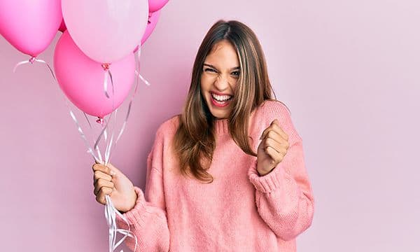 Kvinne holder rosa ballonger