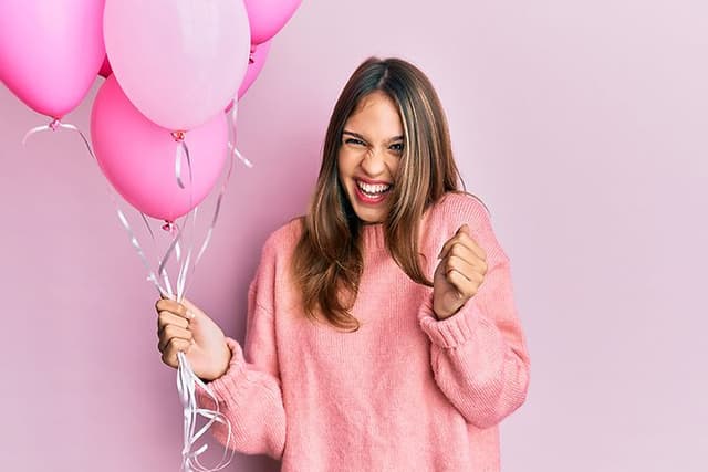Kvinne holder rosa ballonger