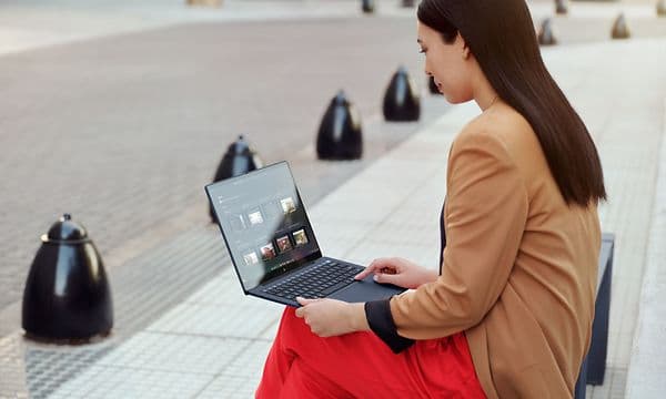 HP - Computing - Woman sitting outside on a bench working with her HP laptop
