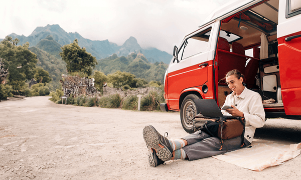 Boy sitting next to a van and working with his Asus ProArt Flip PX13 laptop on his lap