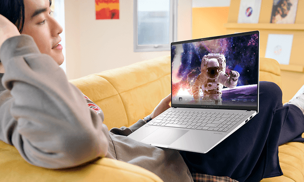 Mies rentoutuu sohvalla Asus Vivobook S 15 -kannettava sylissään