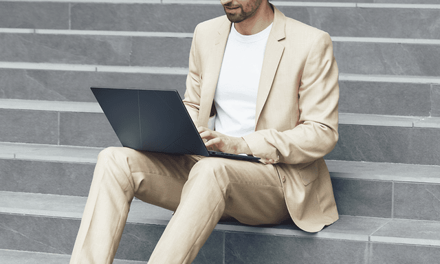 Mies istuu kiviportailla ja työskentelee ASUS Zenbook 14 OLED -kannettavalla
