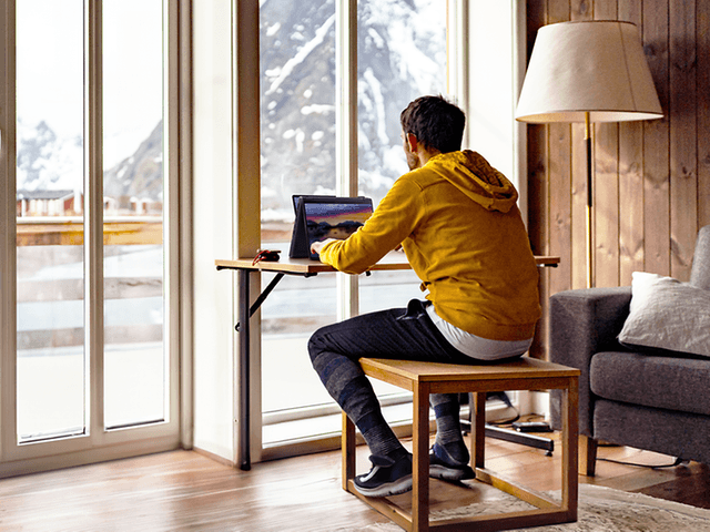 Mand, der arbejder med sin Asus ProArt Flip PX13 bærbare computer og bjerglandskab som udsigt