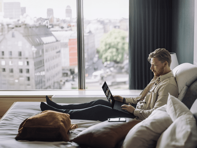 Man on a sofa working with Asus ProArt P16 H7606 laptop on his lap