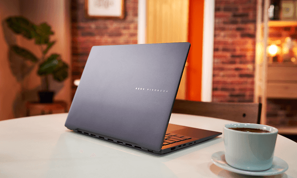 Asus Vivobook S 14 M5406 bærbar på et bord og en kaffekop ved siden af