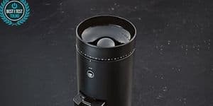 A Wilfa coffee grinder next to coffee beans being weighed on a digital scale, ready for grinding
