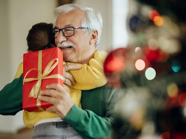 Ett barn ger en julklapp till sin morfar eller farfar