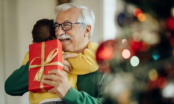 Ett barn ger en julklapp till sin morfar eller farfar