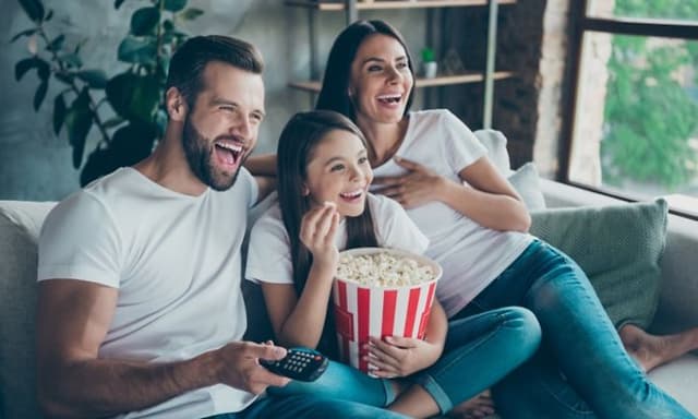 Familie på tre koser seg med hjemmekino og popcorn