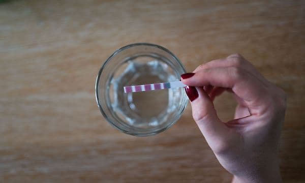Guide - MDA - Woman checking water hardness with a test strip at home