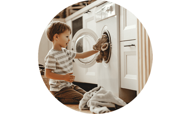 Kid putting teddy bear in washing machine
