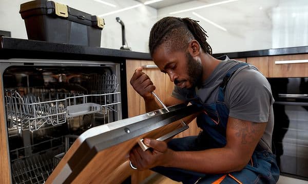 Man using screw driver on dishwasher