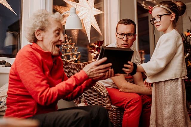 Grandma opening a gift with family surrounding her