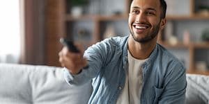 Forsikring af TV: En mand med en fjernbetjening i hånden sidder i en sofa