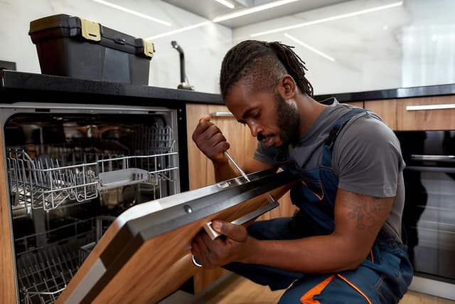 Man using screw driver on dishwasher