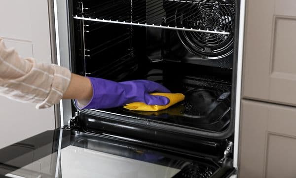 Close-up of a hand cleaning the inside of an oven