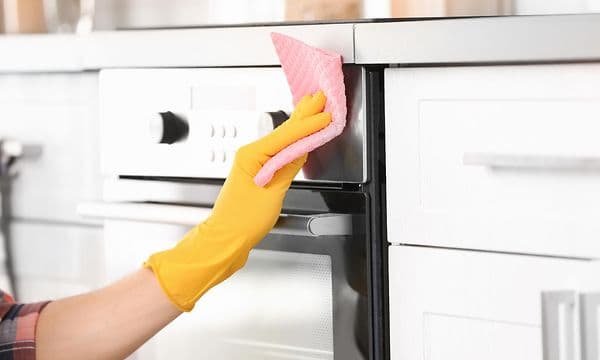 Close-up of a hand cleaning the outside of an oven