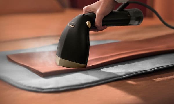 Handhållen steamer - Svart Philips steamer används på brunt tyg.