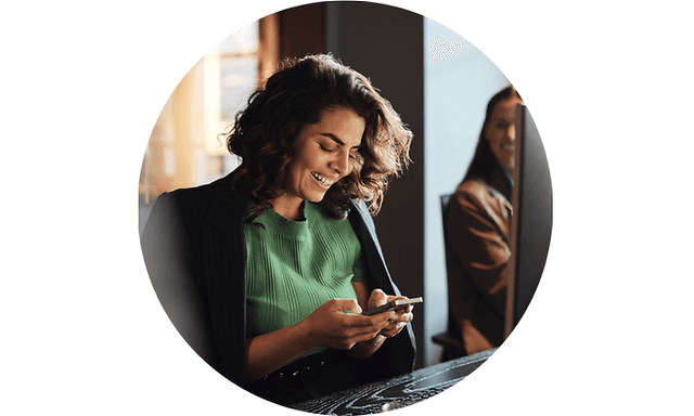 Kvinne smiler mens hun ser på mobilen sin
