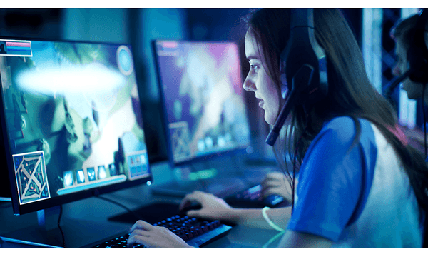 kvinne med gaming-headset spiller dataspill på skjerm