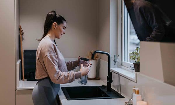 Afkalkning af kaffemaskine foretages af kvinde i et køkken