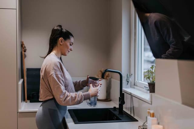 Afkalkning af kaffemaskine foretages af kvinde i et køkken