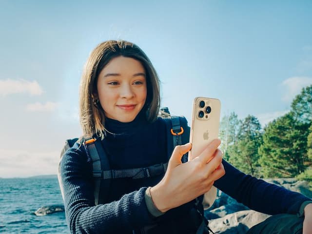 Woman with backpack holding an iPhone 16 Pro