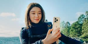 Kvinne med ryggsekk som holder en iPhone 16 Pro