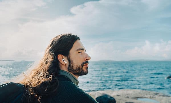 En mann på stranden med AirPods Pro i ørene.