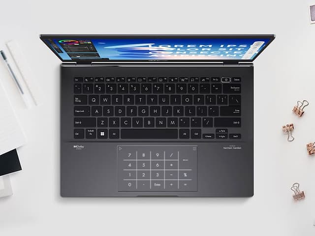 ASUS Zenbook 14 bærbar på et bord omgivet af forskellige kontorartikler