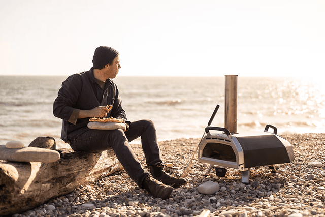 Pizzaovn bedst i test: Mand på strand med en pizzaovn