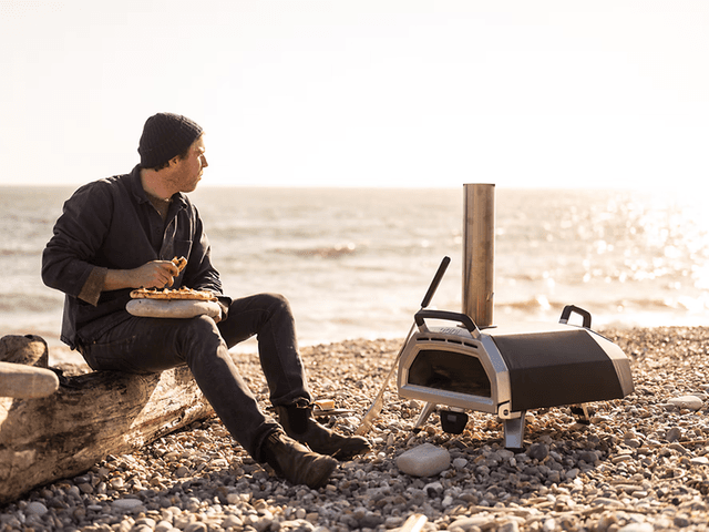Pizzaovn bedst i test: Mand på strand med en pizzaovn