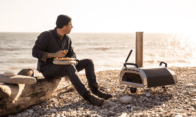 Pizzaovn bedst i test: Mand på strand med en pizzaovn