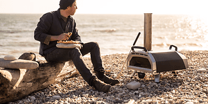 Pizzaovn bedst i test: Mand på strand med en pizzaovn