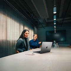 Gigantin yritysneuvonataja auttaa naispuolista yritysasiakastaan MacBook Air -tietokoneen käytössä