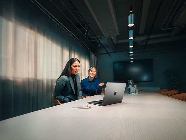 Gigantin yritysneuvonataja auttaa naispuolista yritysasiakastaan MacBook Air -tietokoneen käytössä